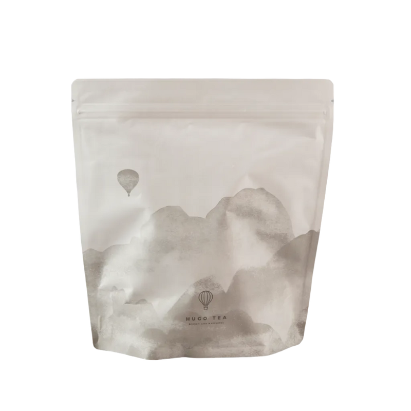 Hugo tea packaging with mountain and hot air balloon design on a gray background