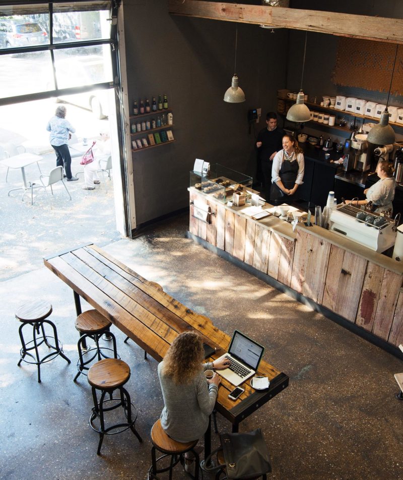 Slow morning inside Roastery cafe with garage door partially open and guest on laptop.