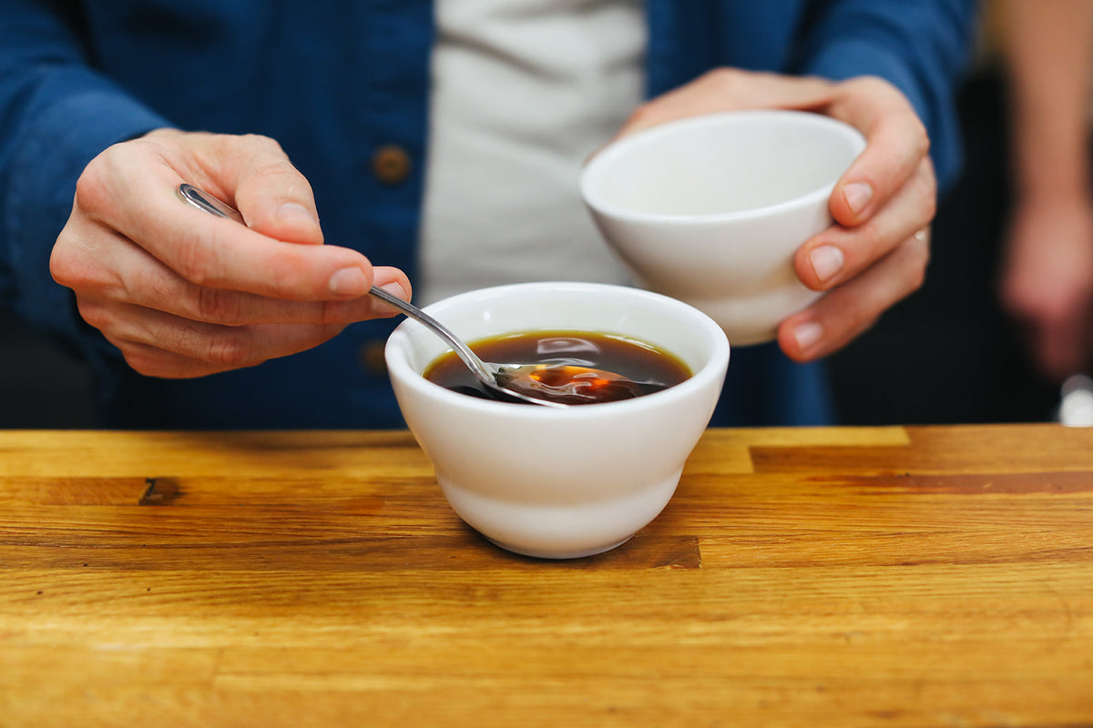 Person stirring coffee in white cup during Sensory Experience - Bethesda coffee tasting event