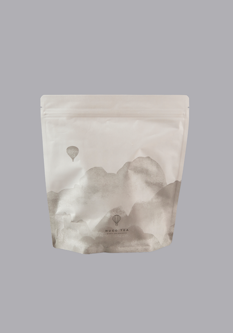 Hugo tea packaging with mountain and hot air balloon design on a gray background