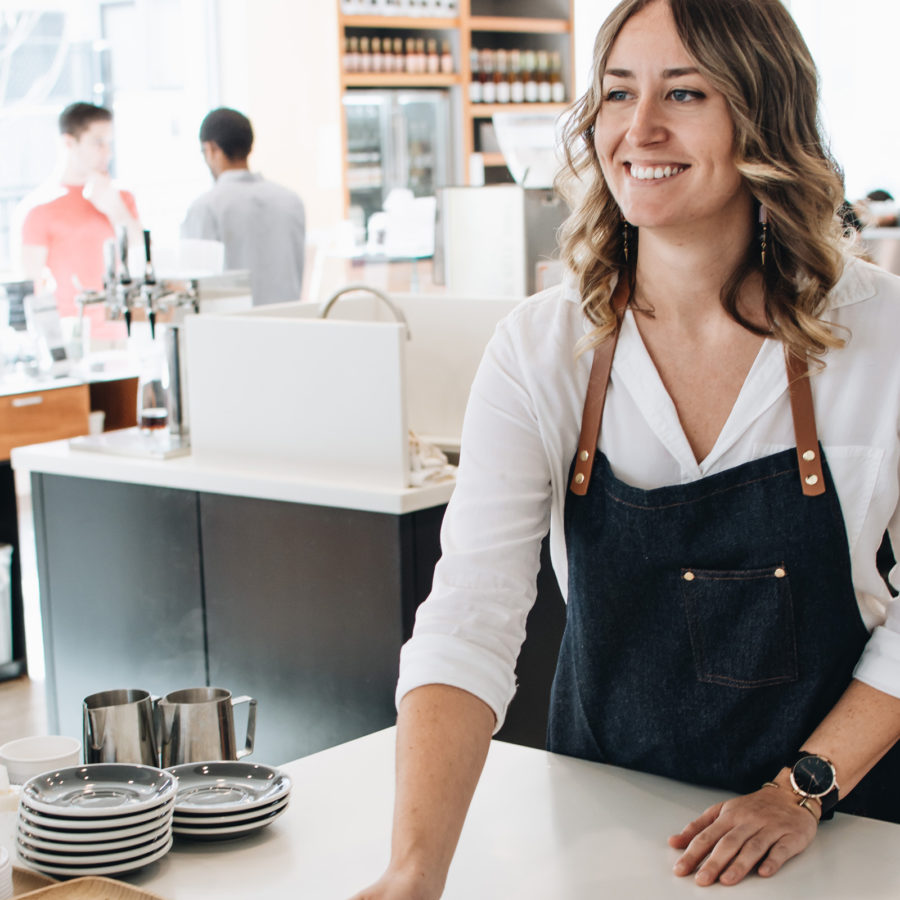 Friendly barista calls out drink and smiles.