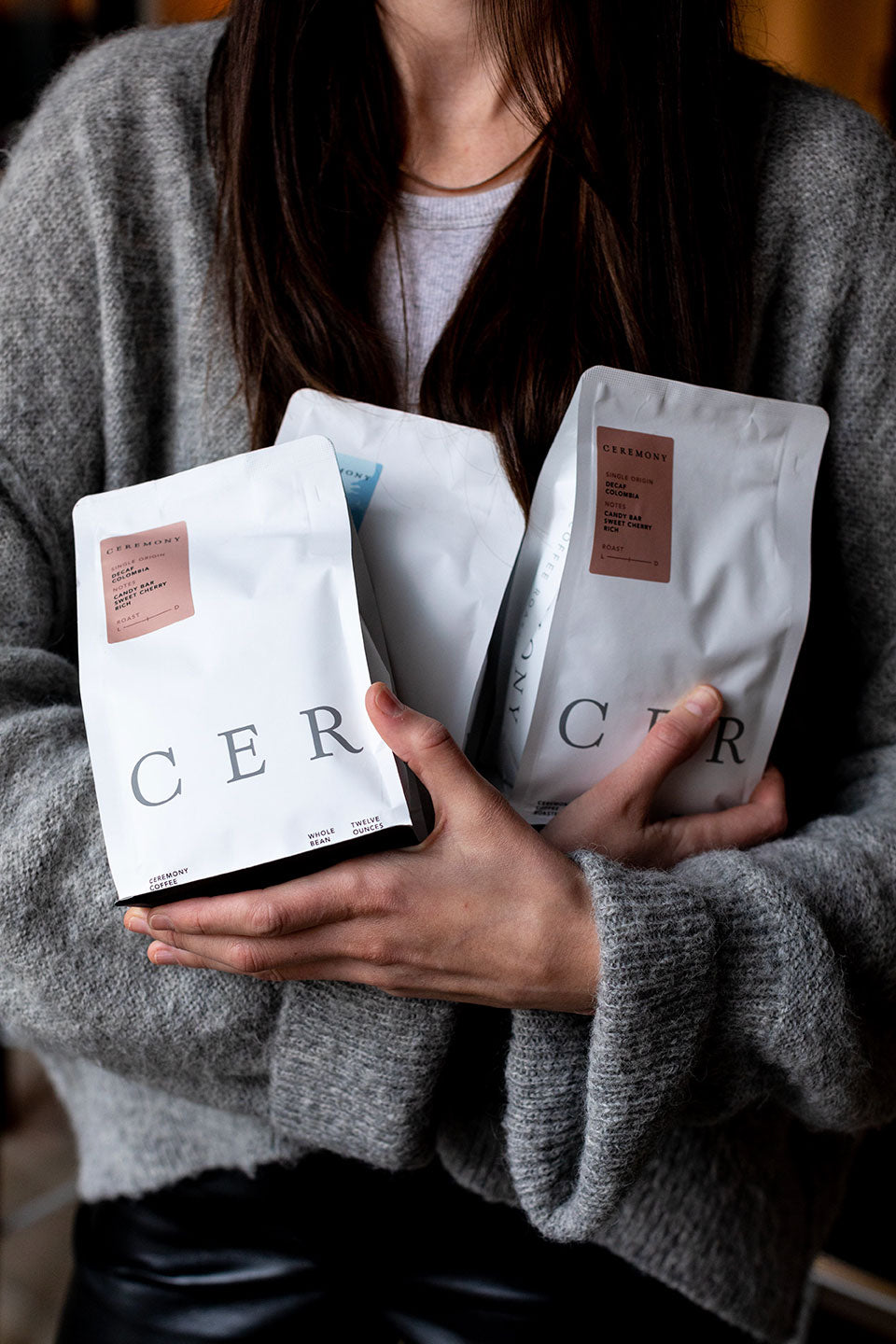 Photo of a woman holding three bags of ceremony coffee blends in here crossed hands.