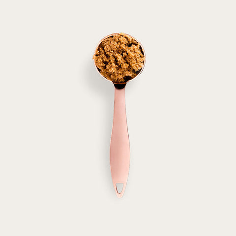 A pink measuring scoop filled with golden-brown Thesis coffee grounds against a cream background, showcasing the 10.00% Off Auto renew subscription product. The scoop features an ergonomic handle and contains finely ground coffee with a rich, textured appearance.
