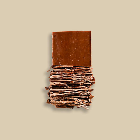 Peru Cenfrocafe 10.00% Off Auto renew - Artfully stacked layers of rich brown chocolate broken into thin, textured pieces, displayed against a neutral beige background, showcasing the delicate, flaky texture and high-quality appearance of the chocolate.
