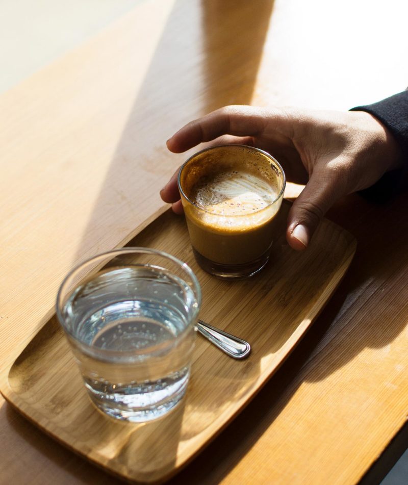 A guest's cortado and sparkling water on a service tray