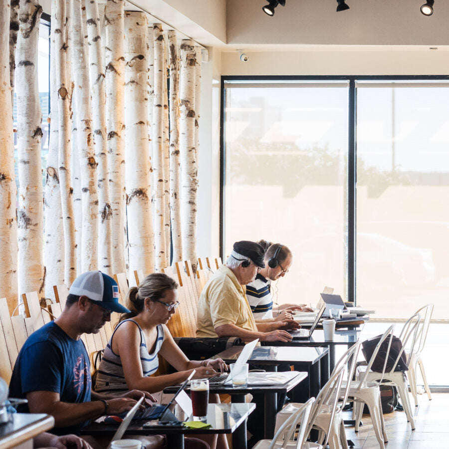 Customers working and drinking coffee at Riva location.