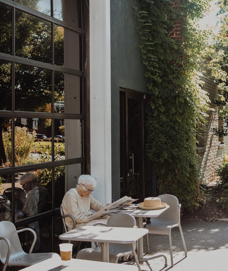 Dedicated customer reading the paper with coffee outside Roastery location.