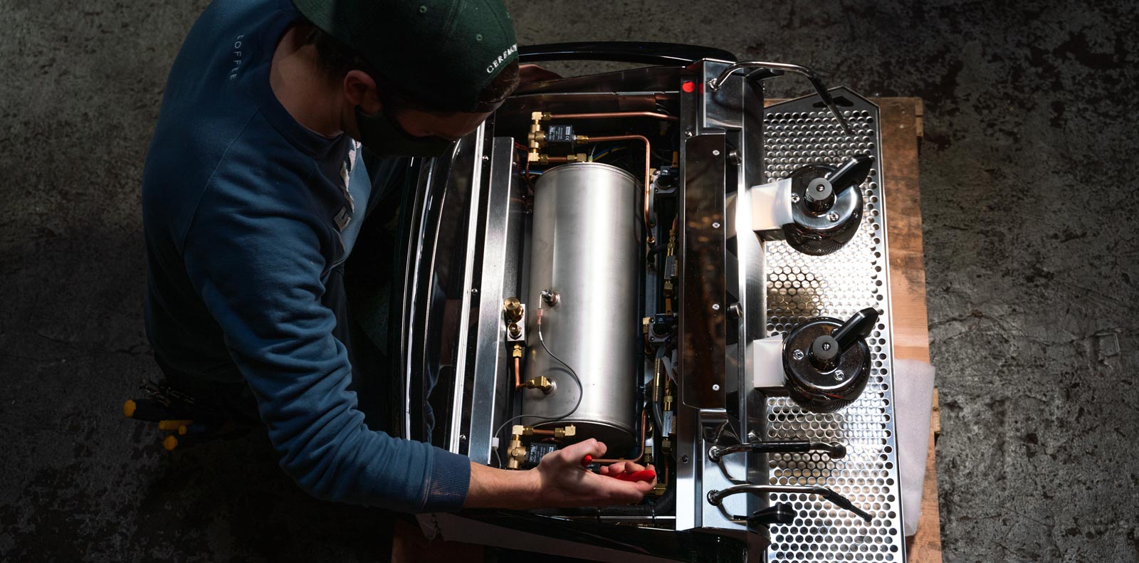 Equipment technician adjusting parts inside of Slayer espresso machine.